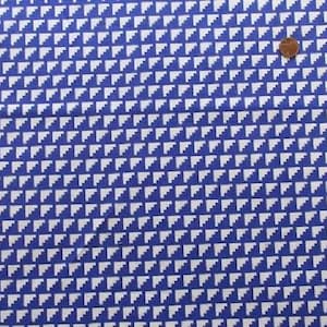 Peut inclure: Un tissu bleu et blanc avec un motif répétitif de petits triangles blancs. Le tissu a une texture subtile.