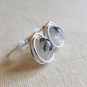 May include: A pair of silver wire wrapped earrings with clear quartz stones that have black inclusions.