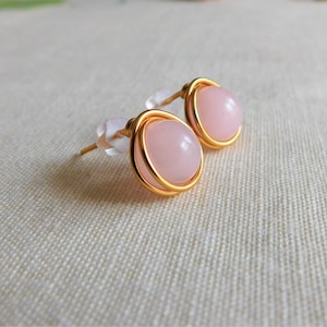 May include: A pair of gold wire wrapped earrings with pink gemstone cabochons.