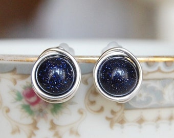 May include: A pair of silver wire wrapped earrings with blue glitter stone cabochons.