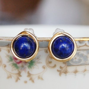Peut inclure: Une paire de boucles d'oreilles en fil d'or avec des pierres rondes en lapis-lazuli bleu.