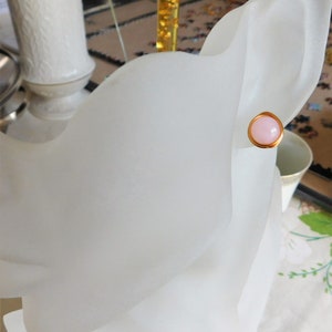 May include: A pair of gold stud earrings with a pink stone in the center.