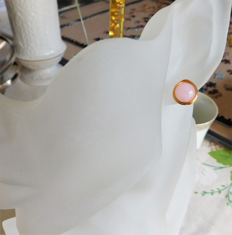 May include: A pair of gold stud earrings with a pink stone in the center.