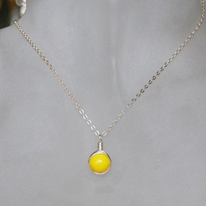 May include: A silver chain necklace with a bright yellow round pendant.
