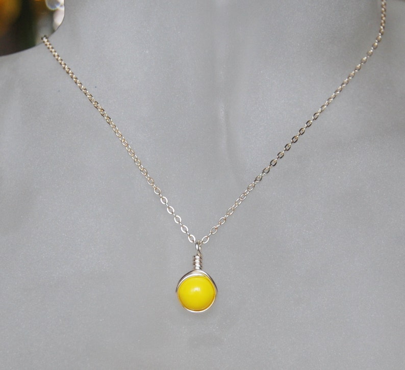 May include: A silver chain necklace with a bright yellow round pendant.