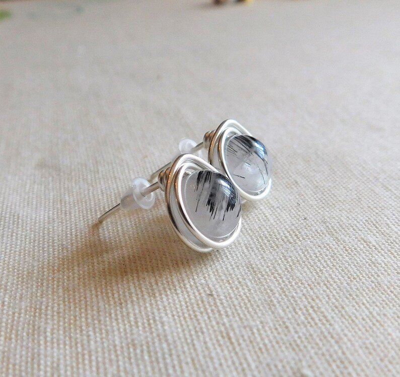 May include: A pair of silver wire wrapped earrings with clear quartz stones that have black inclusions.