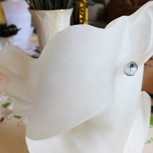 May include: A white ceramic mannequin head with a single silver earring featuring a clear crystal stone.