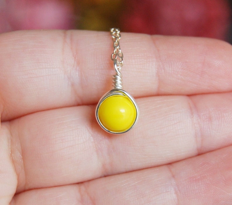 May include: A silver chain necklace with a yellow glass bead pendant.