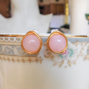 May include: A pair of gold wire wrapped earrings with pink rose quartz stones.