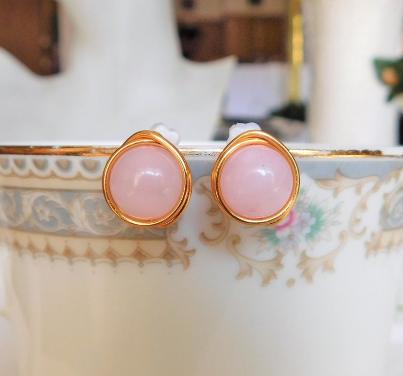 May include: A pair of gold wire wrapped earrings with pink rose quartz stones.