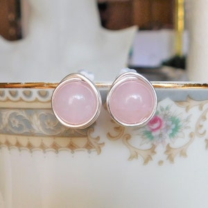 May include: A pair of silver stud earrings with pink rose quartz stones.