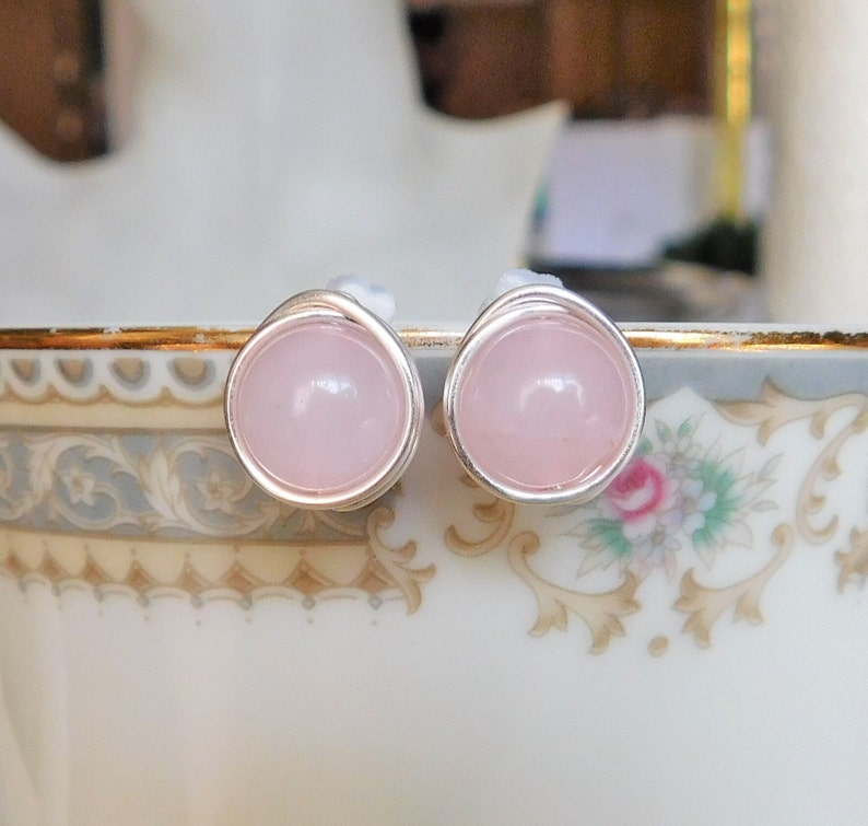 May include: A pair of silver stud earrings with pink rose quartz stones.