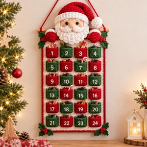 May include: A crocheted wall-hanging advent calendar featuring a Santa Claus head at the top with a red hat and white beard. The calendar has twenty-four numbered pockets in alternating red and green colors, decorated with small festive items.