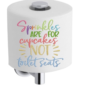 Op de afbeelding: Witte toiletrol met een kleurrijk geborduurd ontwerp met de tekst "Sprinkles are for cupcakes not toilet seats".