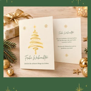 Può includere: Un biglietto d'auguri piegato color crema con un albero di Natale stampato in lamina d'oro e il testo "Frohe Weihnachten" e "Zeit für die schönen Dinge im Leben." L'interno mostra il testo "Frohe Weihnachten," "Zeit zum Innehalten. Zeit zum Lachen. Zeit für Menschen, die unser Leben besonders machen. Wundervolle Weihnachten und ein glückliches neues Jahr!"