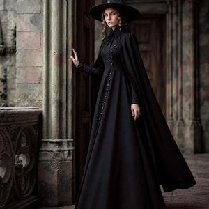 May include: A floor-length black dress with a high collar and a vertical row of buttons down the front, paired with a matching black cape and a wide-brimmed pointed hat. The ensemble features long sleeves and a full, flowing skirt silhouette.