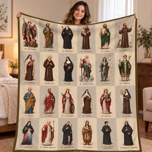 May include: A rectangular throw blanket featuring a grid of twenty-four individual portraits of Catholic saints. Each saint is labeled with their name, including St. Michael, St. Joseph, St. Benedict, St. Anthony, St. Jude, St. Francis, and others.