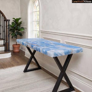 May include: A rectangular console table featuring a polished blue and white stone slab top with natural veining, supported by a black metal X-shaped base. The LuxeWoodNStone logo is visible in the top right corner of the image.