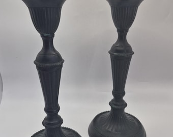 Peut inclure: Une paire de bougeoirs en métal noir mat présentant un design à colonne cannelée, une large base circulaire avec des détails perlés et un bord supérieur évasé. Les bougeoirs ont une finition sombre uniforme et des textures rainurées.