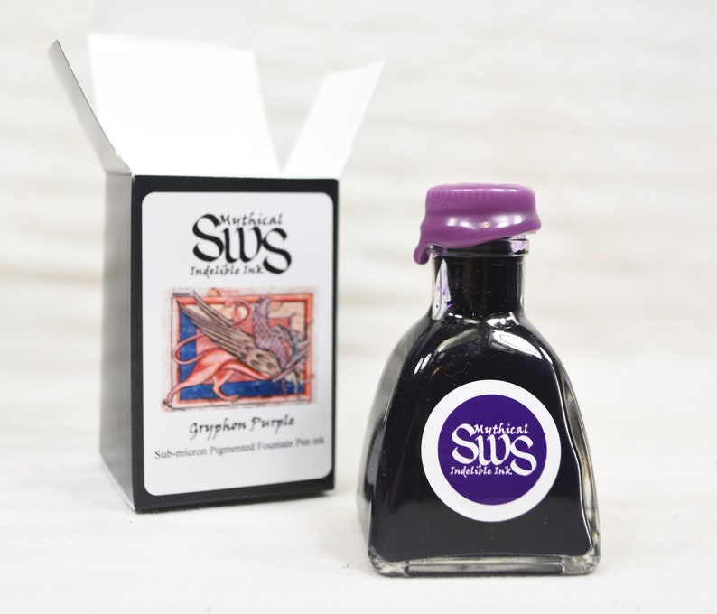 K&ouml;nnte beinhalten: Eine Flasche Gryphon Purple F&uuml;llfederhalter-Tinte mit einem lila Wachssiegel. Die Flasche hat ein wei&szlig;es Etikett mit dem Text "Mythical SWS Indelible Ink". Eine schwarze Schachtel mit dem gleichen Logo und einer Zeichnung einer mythischen Kreatur befindet sich daneben.