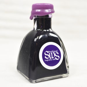 K&ouml;nnte beinhalten: Eine kleine, quadratische Glasflasche gef&uuml;llt mit dunkelvioletter Tinte. Die Flasche hat ein lilafarbenes Wachssiegel und ein wei&szlig;es Etikett mit dem Text "Mythical SWS Indelible Ink" in einem kreisf&ouml;rmigen Design. Die Tinte ist durch das klare Glas sichtbar.