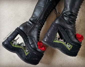 May include: Black platform boots with lace detailing and a red rose embellishment. The platform features a lace-covered window with a miniature graveyard scene.