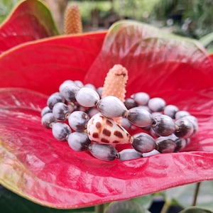 May include: A white ceramic mug with a black handle and the text "But First, Coffee" in a black, handwritten-style font. The mug is on a white surface.