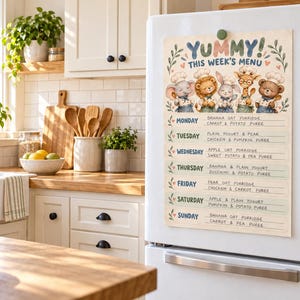 May include: A magnetic weekly meal planner chart attached to a white refrigerator. The header reads YUMMY! THIS WEEK'S MENU above illustrations of five animals in chef hats. Each day from Monday to Sunday includes lines for food entries.