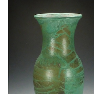 May include: A tall, green ceramic vase with a textured, marbled glaze. The vase has a slender, elegant shape.