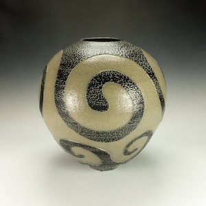 May include: A ceramic vase with a textured, off-white glaze and black swirling patterns.