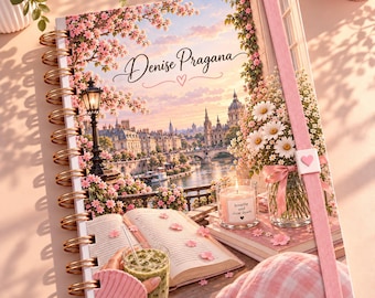 May include: A spiral-bound notebook featuring a cover illustration of a European cityscape at sunset with cherry blossoms, an open book, a glass of green drink, a candle labelled breathe and slow down, and a pink elastic band with a heart.