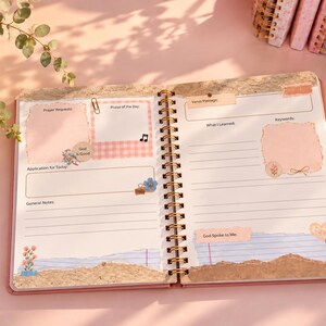 May include: An open spiral-bound prayer journal with pink and cream pages featuring sections for Prayer Requests, Praise of the Day, Verse, What I Learned, Keywords, Application for Today, General Notes, and God Spoke to Me with floral accents.