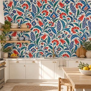 Könnte beinhalten: Eine Küchenwand zeigt ein florales Muster mit roten Tulpen, blauen Hyazinthen und grünen Blättern auf weißem Grund. Zwei helle Holzregale tragen weiße Schüsseln und einen Krug. Weiße Schränke, ein goldener Wasserhahn und ein Holztisch sind zu sehen.