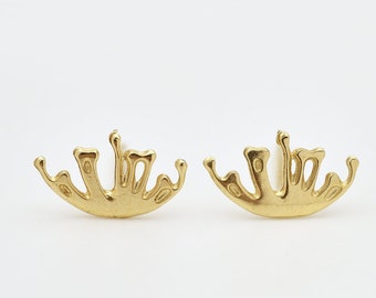 May include: A pair of gold-colored earrings with a unique abstract design, resembling a stylized splash of liquid.