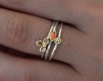 Könnte beinhalten: Ein Set aus drei zarten Ringen mit einer goldenen und silbernen Oberfläche. Die Ringe haben kleine, bunte Edelsteine und ein Blattdesign.