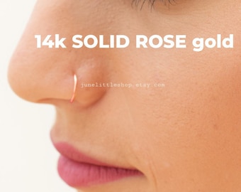 Może przedstawiać: Zbliżenie na twarz osoby z małym, cienkim, różowym pierścionkiem do nosa. Tekst "14k SOLID ROSE gold" i "junelittleshop.etsy.com" jest widoczny pod pierścionkiem do nosa.