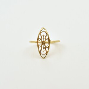 Puede incluir: Un anillo de oro con un delicado dise&ntilde;o calado en forma de &oacute;valo. El anillo est&aacute; hecho de una fina banda de metal y presenta un patr&oacute;n intrincado de l&iacute;neas y curvas.