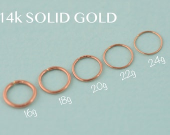 May include: Six gold hoop earrings of different sizes, ranging from 16 gauge to 24 gauge. The earrings are displayed on a light blue background. 14k SOLID GOLD is written at the top of the image.