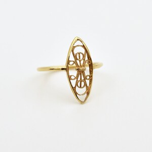 May include: A gold ring with a delicate, openwork design in the shape of an oval. The design features intricate swirls and curves.