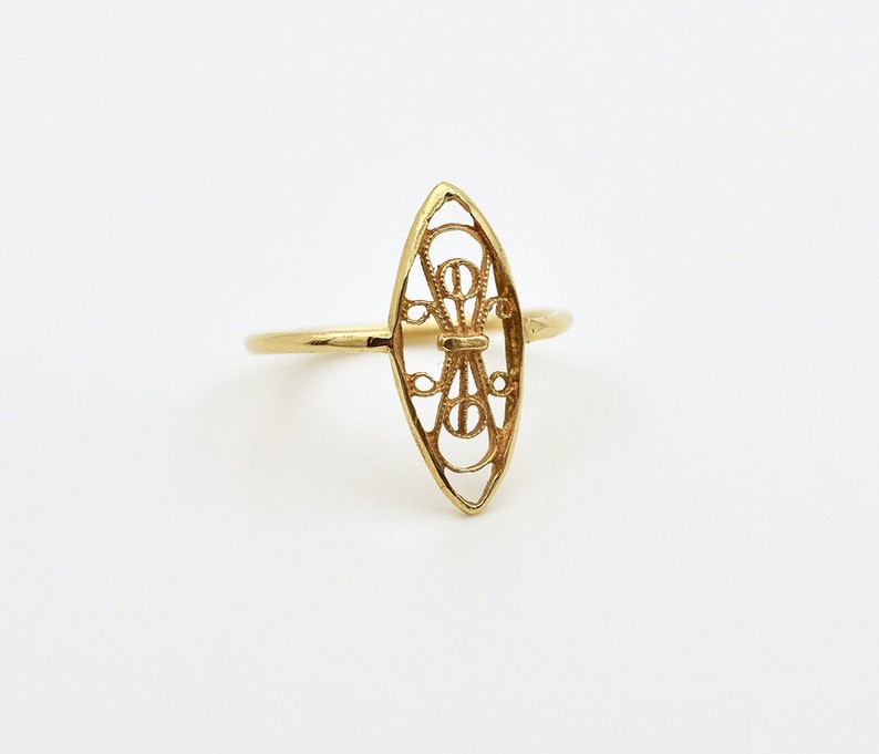 Puede incluir: Un anillo de filigrana dorada con un delicado dise&ntilde;o de forma ovalada. El anillo est&aacute; hecho de un trabajo de metal fino e intrincado y tiene un toque delicado y femenino.