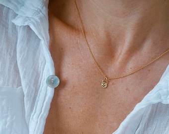 May include: A gold chain necklace with a small padlock pendant. The necklace is worn by a person wearing a white button-down shirt.