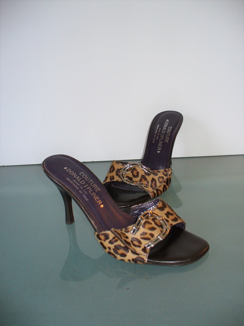 Puede incluir: Una taza de cer&aacute;mica blanca con un asa negra y el texto "But First, Coffee" en negro, con una fuente de estilo manuscrito. La taza est&aacute; sobre una superficie blanca.