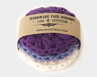 Peut inclure: Gommage visage fait main en 100% coton. Le gommage est composé de couches de couleur violette, bleue et crème. L'emballage est en papier brun avec le texte "Handmade Face Scrubby * 100% Cotton * www.rightsoap.com"