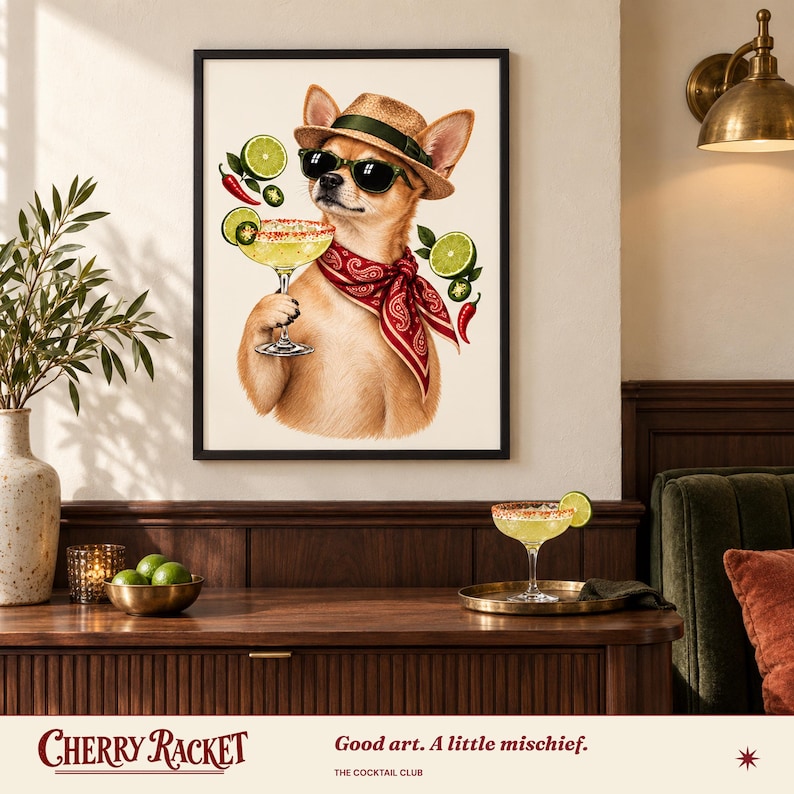 Op de afbeelding: Een ingelijste kunstdruk met een beige chihuahua die een strooien hoed, zwarte zonnebril en een rode paisley bandana draagt. De hond houdt een margaritaglas vast, omringd door zwevende limoenschijfjes en rode chilipepers op een cr&egrave;mekleurige achtergrond.