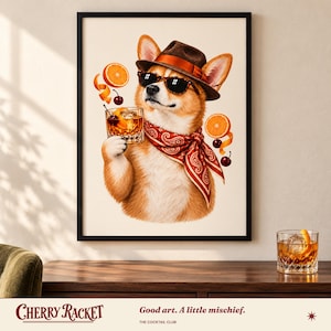 May include: A framed wall art print featuring a tan and white Corgi wearing a brown fedora, black sunglasses, and a red paisley bandana. The dog holds a glass of amber liquid with a cherry and orange slice, surrounded by floating orange slices and cherries.