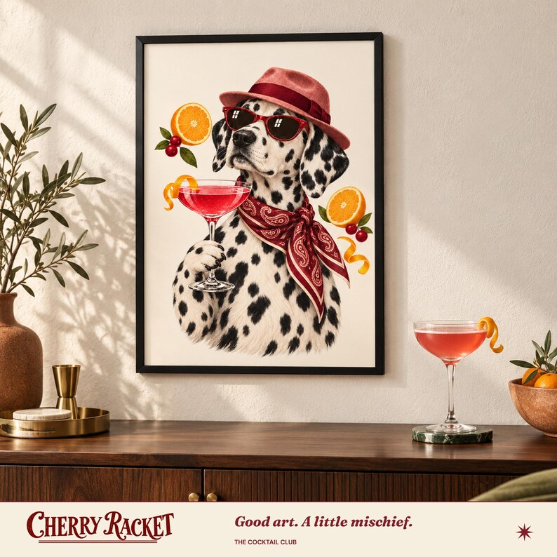 May include: A framed wall art print featuring a Dalmatian dog wearing a red fedora, red sunglasses, and a red paisley bandana. The dog holds a pink cocktail glass, surrounded by orange slices and cherries. The text reads Cherry Racket.