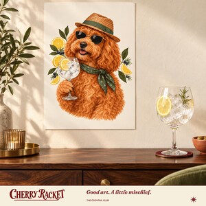 May include: A wall art print featuring a fluffy ginger dog wearing a straw fedora, dark sunglasses, and a green patterned neckerchief. The dog holds a glass of gin and tonic garnished with a lemon slice, surrounded by lemon and juniper illustrations.
