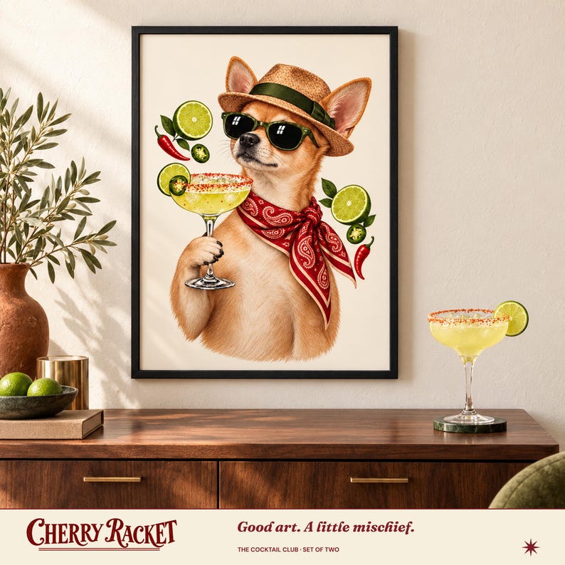 May include: A framed wall art print featuring a tan chihuahua wearing a straw fedora, black sunglasses, and a red paisley bandana. The dog holds a margarita glass garnished with lime slices and chili peppers, set against a cream background.