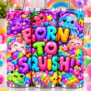 May include: A cylindrical tumbler featuring a vibrant, multi-colored design with the text "BORN TO SQUISH!" surrounded by illustrations of a purple cat, a unicorn, a frog, a jellyfish, a dumpling, and various colorful shapes.