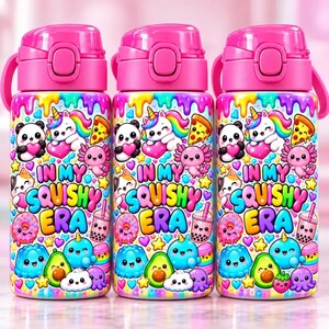 May include: Three identical water bottles with bright pink lids and a colorful pattern featuring cartoon pandas, unicorns, axolotls, avocados, and donuts. The text "IN MY SQUISHY ERA" is printed in large, multi-colored bubble letters.